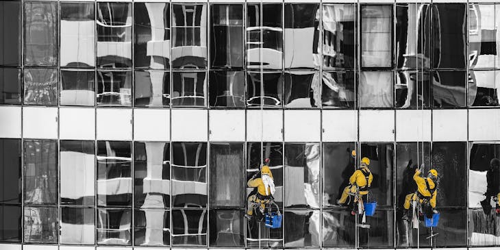 Homens limpando janelas no exterior de um prédio.