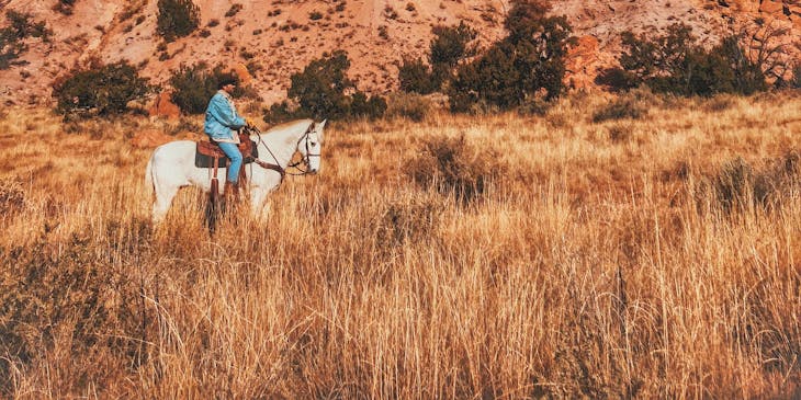 La imagen de hombre a caballo cerca de las montañas en una empresa de Nuevo México.